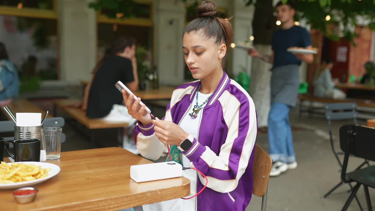 mujer joven comiendo al aire libre y usando su teléfono móvil
