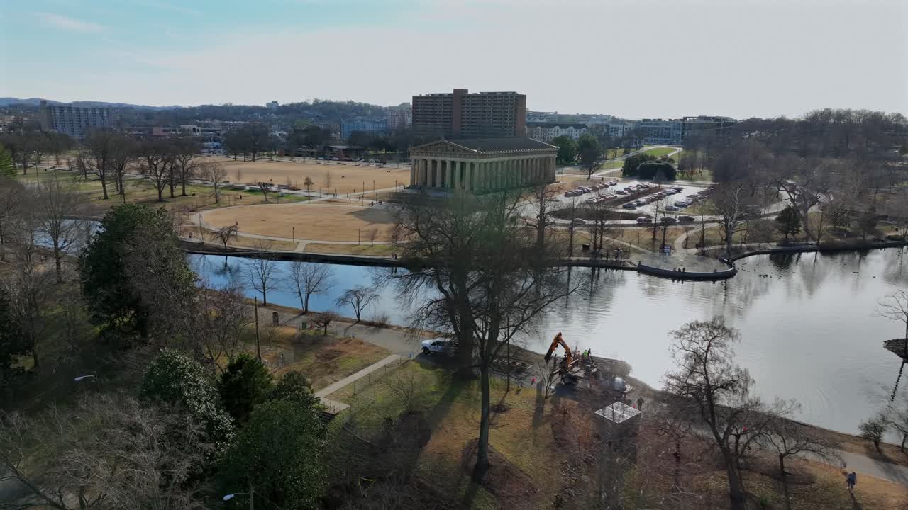 Partenón en Nashville, Tennessee, rodeado por el lago y los senderos del Centennial Park. Monumento icónico con el perfil urbano de la ciudad de fondo a plena luz del día. Toma aérea de aproximación.