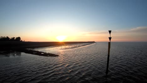 pole in the middle of the water by the shore at the sunset drone aerial footage birds eye view