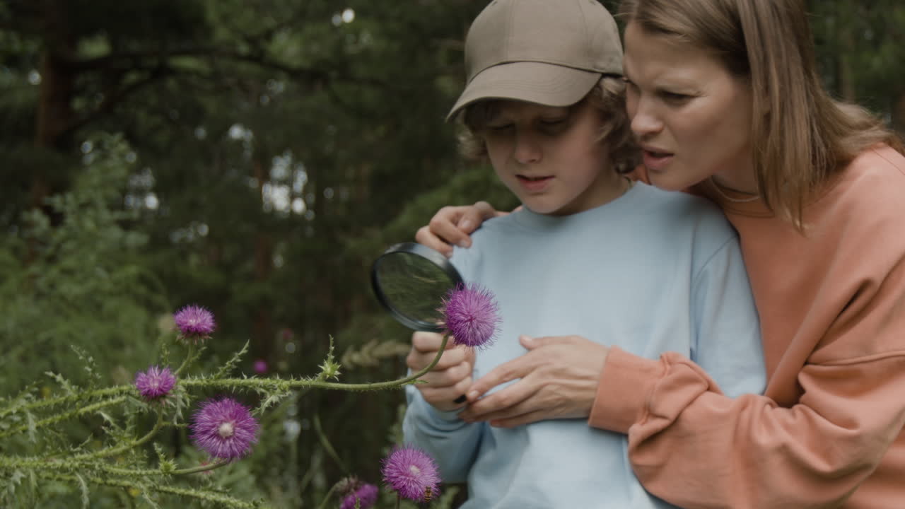 Boy and mother exploring nature with magnifying glass
