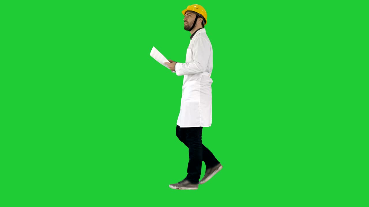 Engineer manager walking with hard hat is holding paper and checking on a Green Screen, Chroma Key