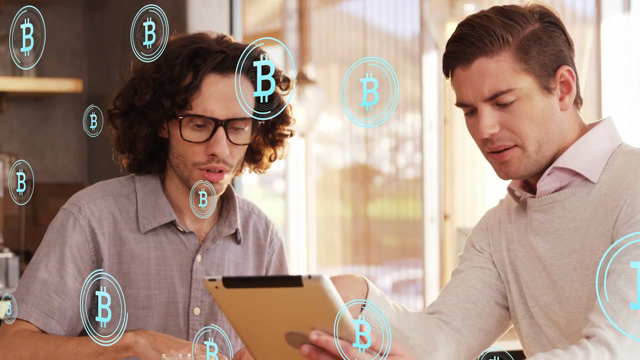 Uomo a destra che tiene un tablet e indica, uomo a sinistra che tocca, mentre esaminano dati Bitcoin, con icone animate in crescita.