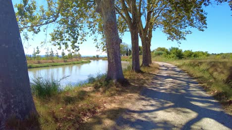 Canal-Du-Midi-France-shelter-under-trees-at-mid-day-on-a-scenic-bend-in-the-canal-on-a-very-warm-September-day