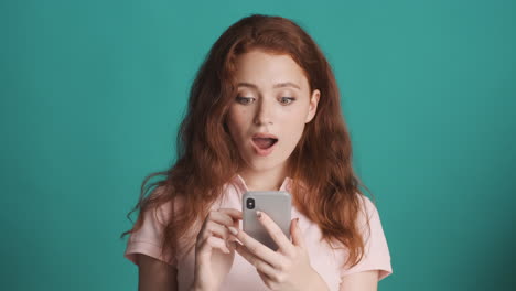 redheaded girl in front of camera on turquoise background.