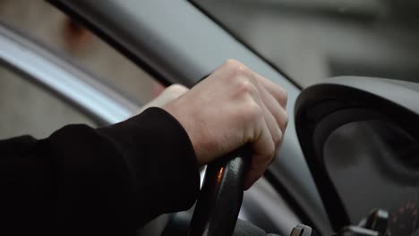 man putting his hands on a black leather steering wheel and holding it tight