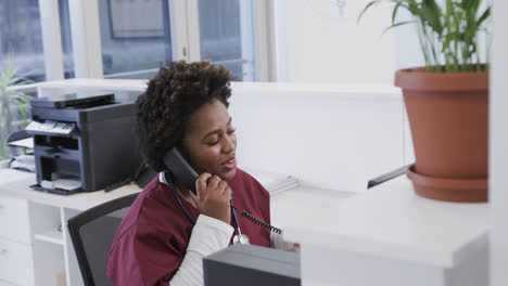 Happy-african-american-female-doctor-talking-on-phone-in-hospital,-slow-motion