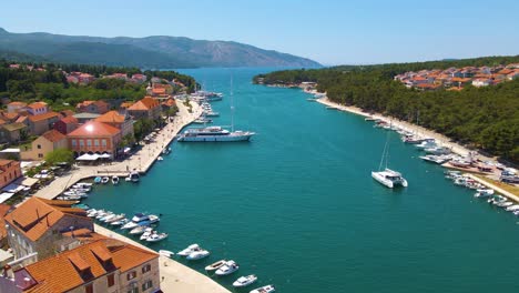 panorama of a coastal town with many houses with red roofs, surrounded by the sea and mountains with yachts in marina bay and bell tower