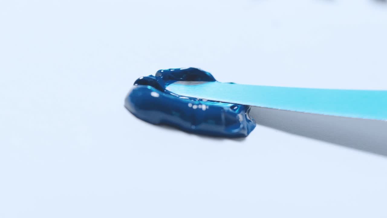 la pintura azul marino se extiende sobre una superficie blanca con un cuchillo de pintores acrílicos