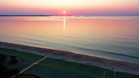 Vista-Aérea-Por-Drones-De-La-Puesta-De-Sol-Sobre-Casas-De-Playa-Con-Colores-Que-Se-Reflejan-En-Las-Olas-Del-Océano-Y-Casas-De-Vacaciones-A-Lo-Largo-De-La-Costa-Atlántica-De-Nueva-Inglaterra