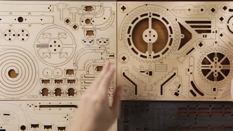 woman hands showing pre-cut mechanical wooden sheets puzzle toy on a table