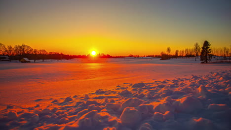 bello amanecer sobre un paisaje invernal con los colores naranja y rojo reflejándose en la nieve blanca en los campos