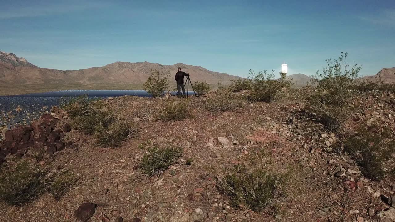antena de drones de un fotógrafo parado en la cima de una colina con vista a una enorme matriz de energía solar primm nevada 2