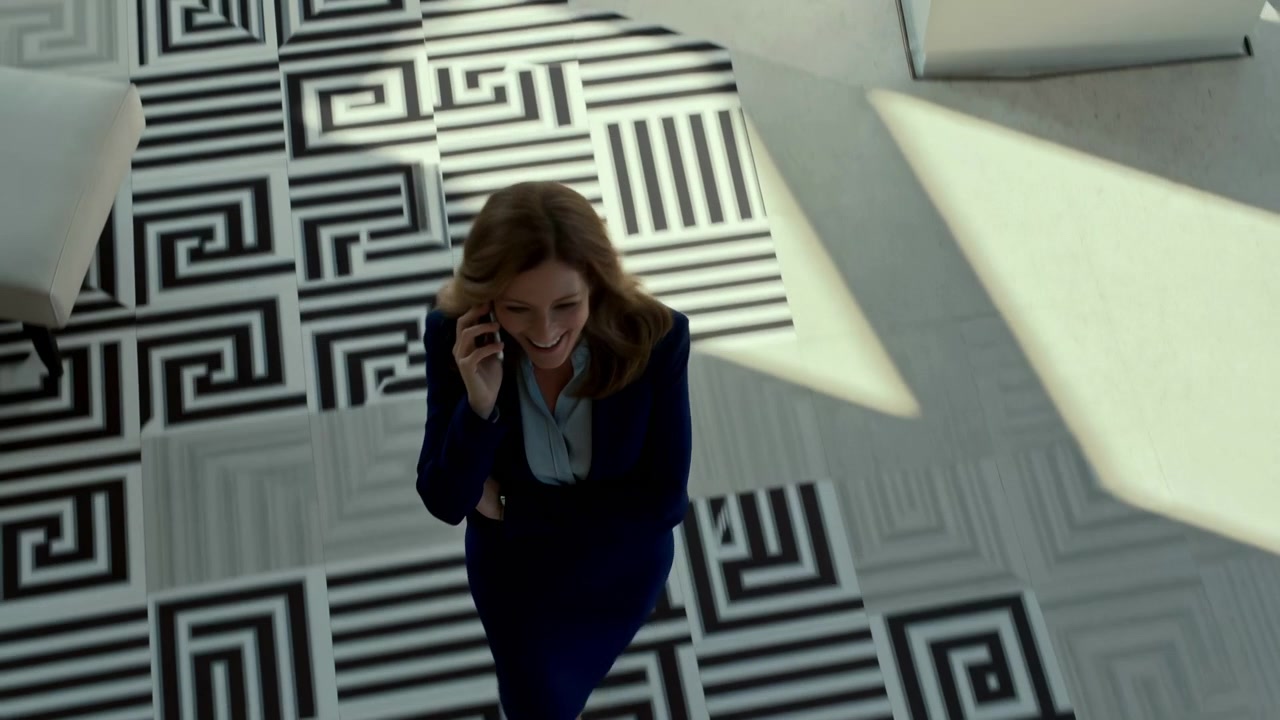 High-angle shot of professional woman standing on geometric black-and-white staircase landing while speaking on smartphone