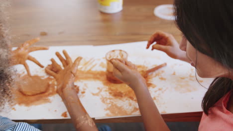 Over-shoulder-view-of-two-pre-teen-girls-playing-with-modelling-clay-at-home,-close-up