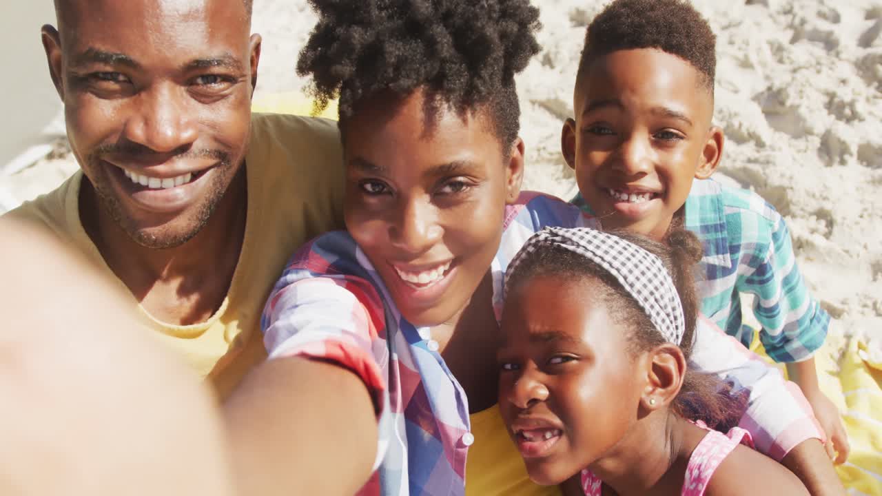 портрет афроамериканской семьи, улыбающейся во время селфи на пляже.