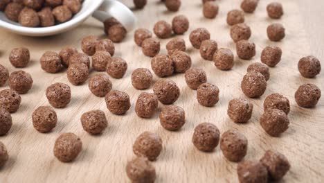 las bolas de cereales de chocolate están esparcidas por el tablero con una taza de té blanca