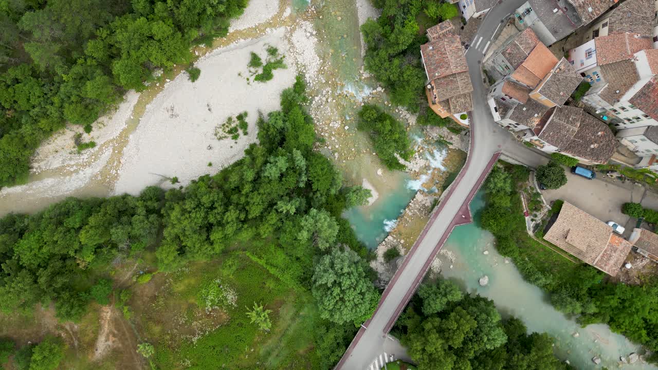 Birds eye view of a river and forrest next to a historic and small mountain village in the south of france.