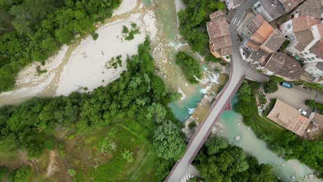 birds eye view of a river and forrest next to a historic and small mountain village in the south of france.