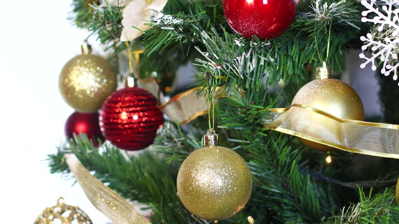 poniendo un adorno de navidad de brillo dorado en el árbol de navidad