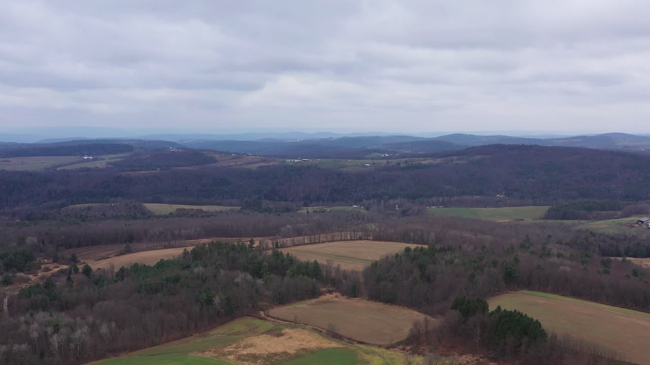 Aerial flyover beautiful Pennsylvania, USA countryside with hills in background and forest during cloudy sky