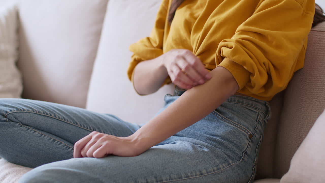 Woman scratching her arm on a couch