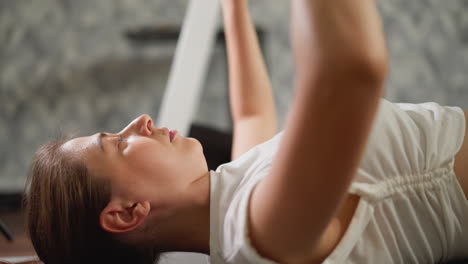 woman raises arms with dumbbells in hands. committed sports enthusiast dedicates herself to sculpting arm muscles using weights in home fitness space