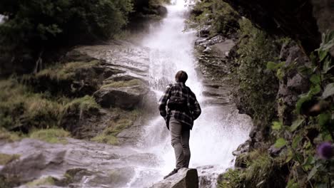 Man-standing-in-front-of-a-beautiful-waterfall,-very-relaxing,-Slow-motion-shot-at-day-time-in-Norway,-Europe