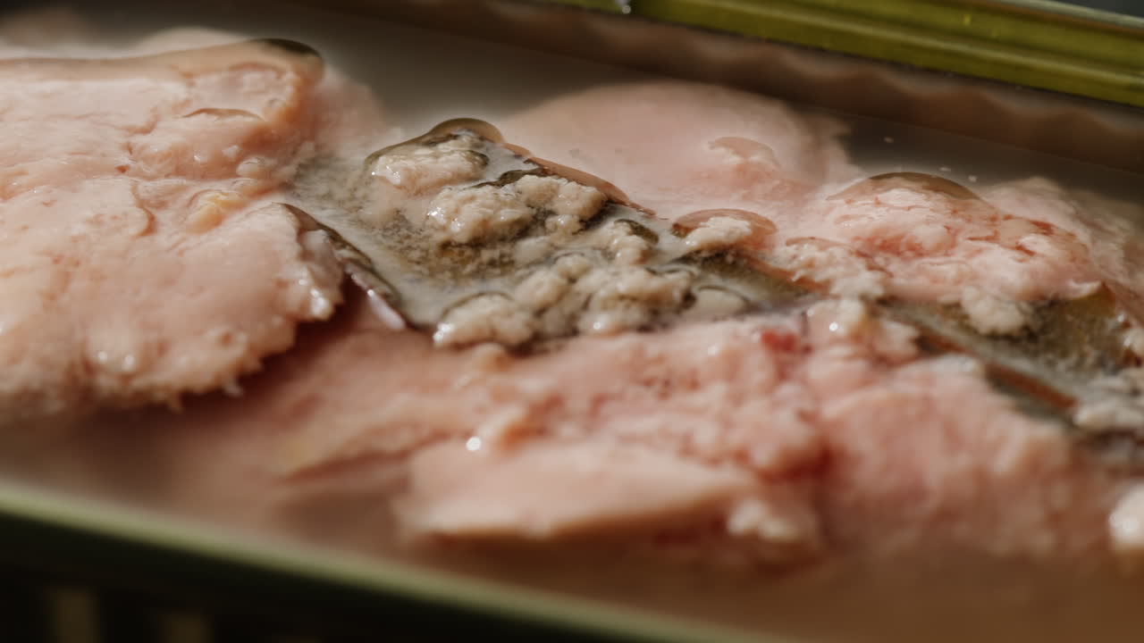 Smoked cod liver in oil in open tin can with fresh greens on wooden table. Seafoods delicacy. High quality 4k footage