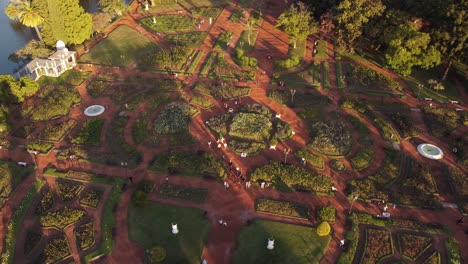 people walk at dusk in rosedal garden park with beautiful symmetric rose art, buenos aires in argentina