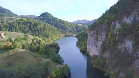 Breathtaking-establishing-aerial-shot-of-lake-in-mountains,-green-forest-summer-day