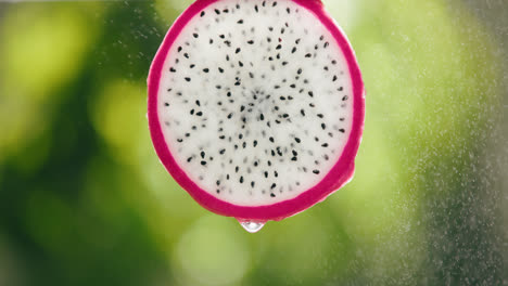 Rebanada-De-Fruta-De-Dragón-Salpicada-Por-Una-Fuerte-Neblina-De-Gotas-De-Agua-Con-Goteo-Líquido-En-Un-Fondo-Retroiluminado-Brillante-En-Cámara-Lenta