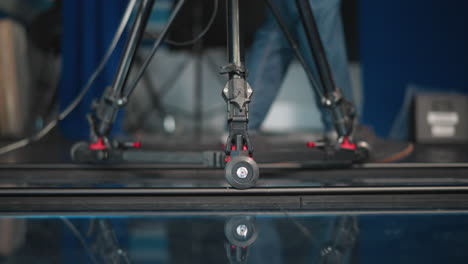 close-up of camera dolly wheel rolling on track in professional studio. clear reflection of equipment on glossy floor. focus on smooth movement and precision of camera rig in action