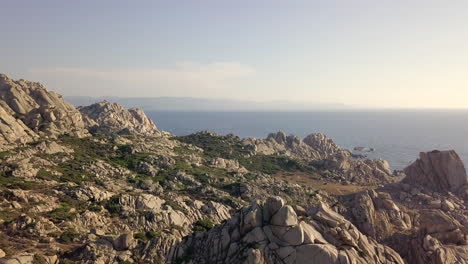 drone shot flying over a rocky cliff revealing the ocean behind it