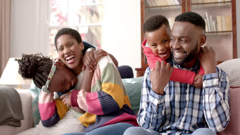 Portrait-of-happy-african-american-parents,-son-and-daughter-siting-on-sofa-in-house,-slow-motion