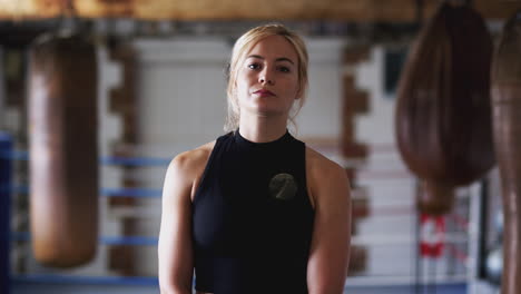 portrait of female boxer in gym training with old fashioned punching bags