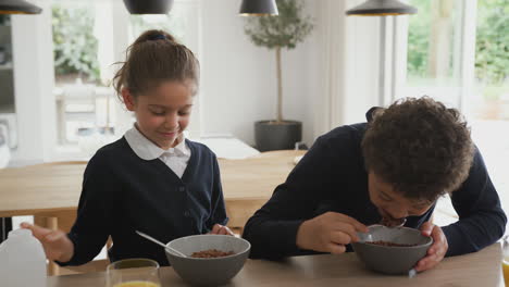 niños en el mostrador de la cocina comiendo un desayuno azucarado antes de ir a la escuela