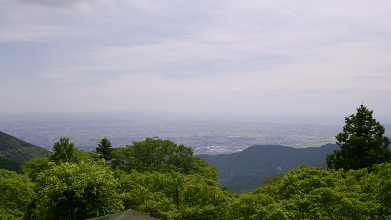 Locked off tripod shot over wide open countryside with lush summer greens and ocean in distance