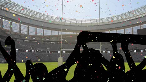 confeti colorido cayendo contra la silueta de los fanáticos aplaudiendo y el estadio deportivo en el fondo