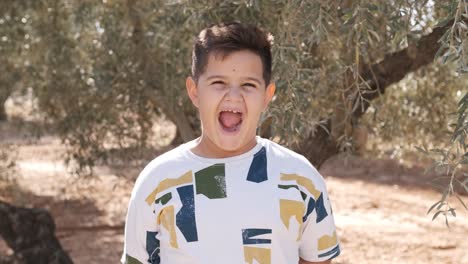 young boy smiling at the camera in the middle of a field