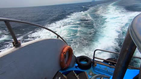 view from back of boat looking over the wake from boat with rescue life buoy, railing and steps in 4k