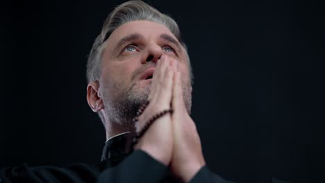 catholic priest praying with beads in hands, christian faith, believing in god