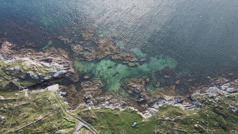 gorgeous coral reef under the clear blue sea by the rocky coastline at the coral strand beach in connemara, ireland - aerial