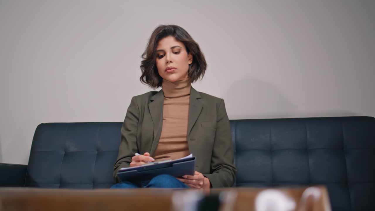 Close-up de um administrador sério envolvido com a papelada, sentado em um sofá confortável de escritório