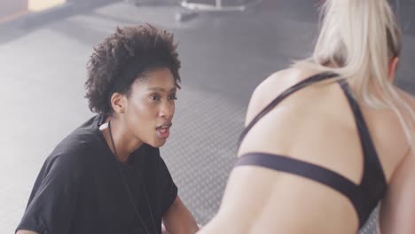 Video-of-diverse-female-trainer-and-woman-talking-after-working-out-at-a-gym