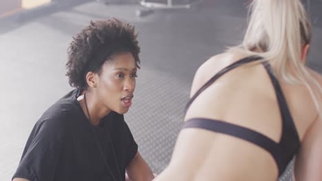 video of diverse female trainer and woman talking after working out at a gym