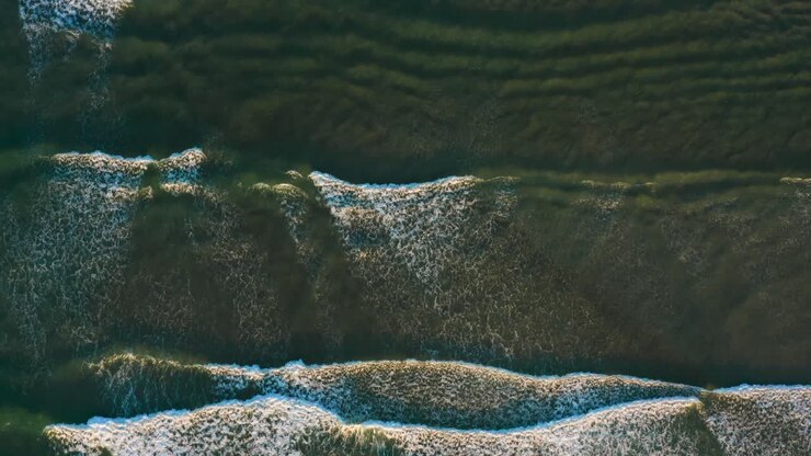 Golden Hour Aerial of Waves Crashing Softly, with the Drone Flying Along Their Path From Above