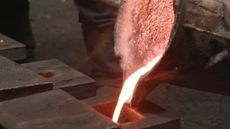 pouring incandescent liquid melting iron into a mold from a bucket