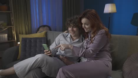 couple watching something on phone on couch