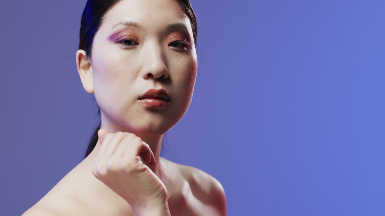 검은 머리카락과 메이크업을 가진 아시아 여성이 카메라를 보고, 공간을 복사, 느린 동작