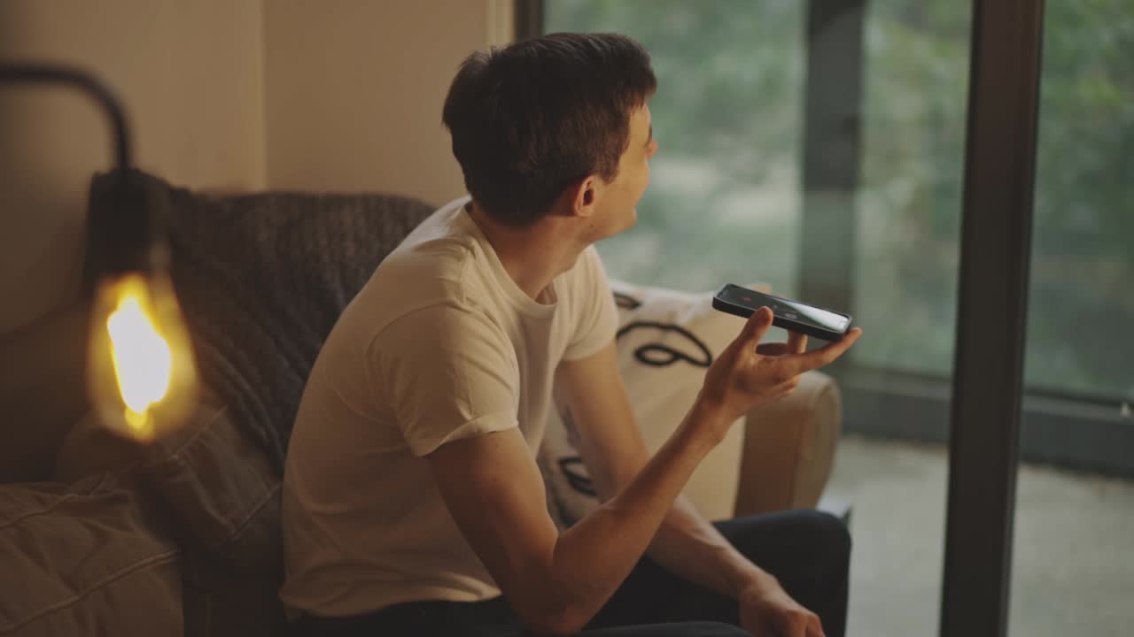 집 에 라우드 스피커 가 있는 전화 통화 에서 웃고 있는 젊은 남자 의 초상화